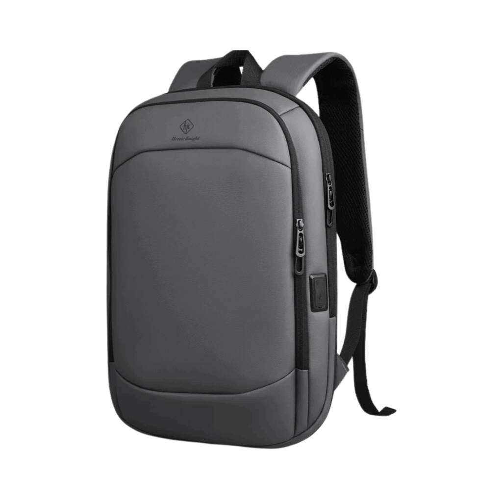 Auf weißem Hintergrund ist ein eleganter, grauer Laptop-Rucksack 17 Zoll mit schwarzen Riemen, einer Reißverschlusstasche vorne und einem seitlichen USB-Ladeanschluss abgebildet.